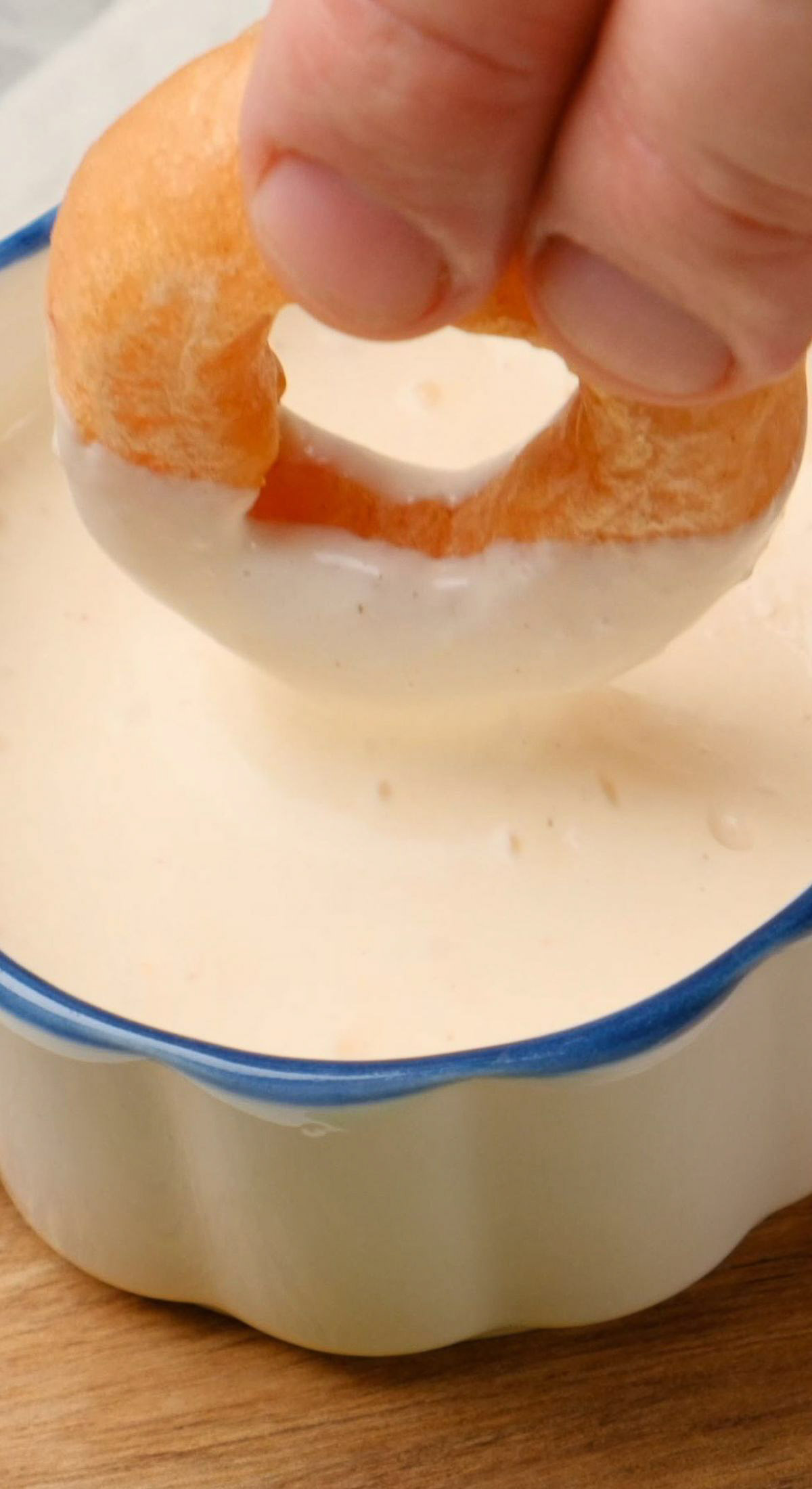 A vegan onion ring being dipped in plant-based mayo.