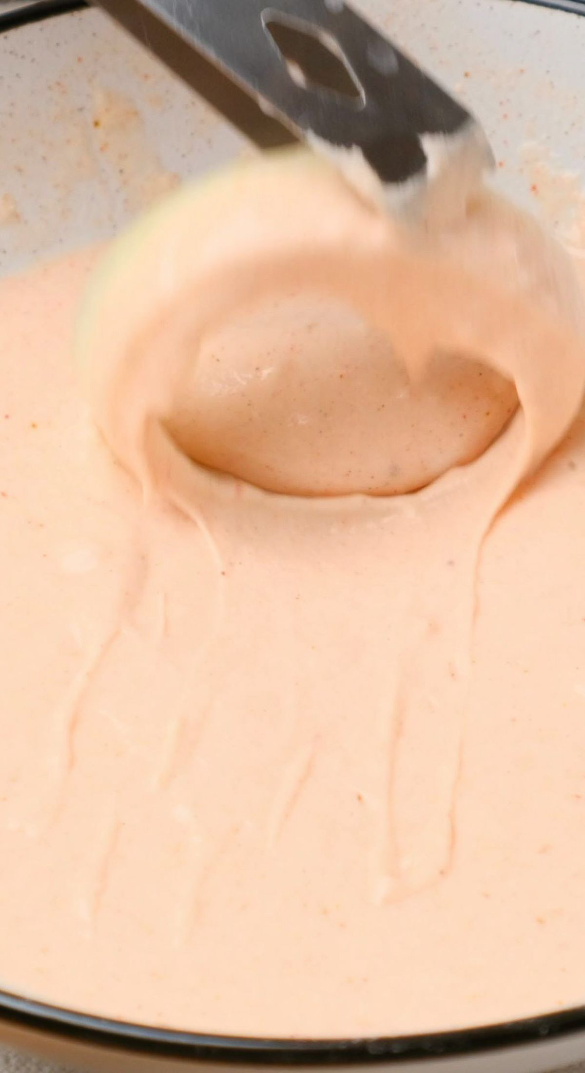 An onion slice being dipped in a vegan batter.