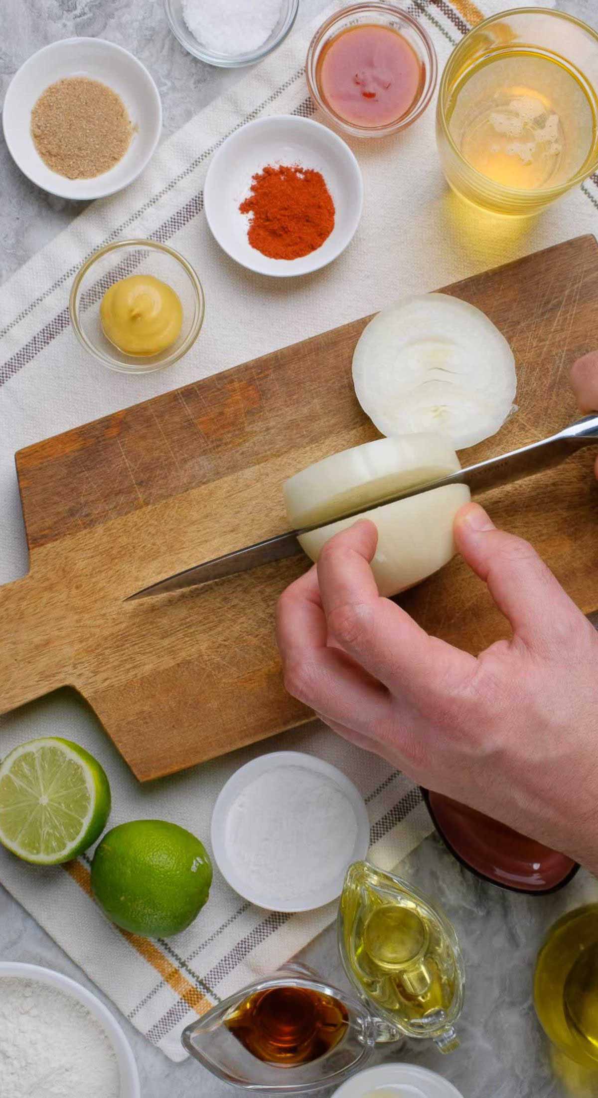 Onions being cut on a wooden board.