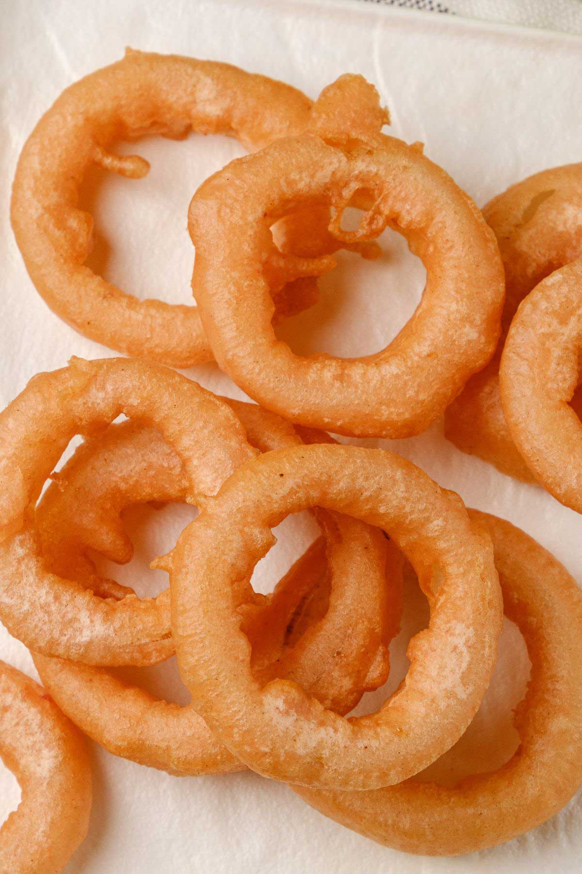 Golden vegan onion rings on a tabletop.