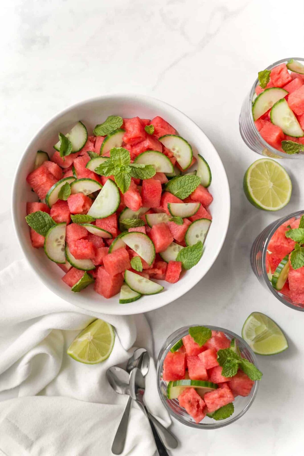 Easy cucumber melon salad served in bowls with a side of lime.