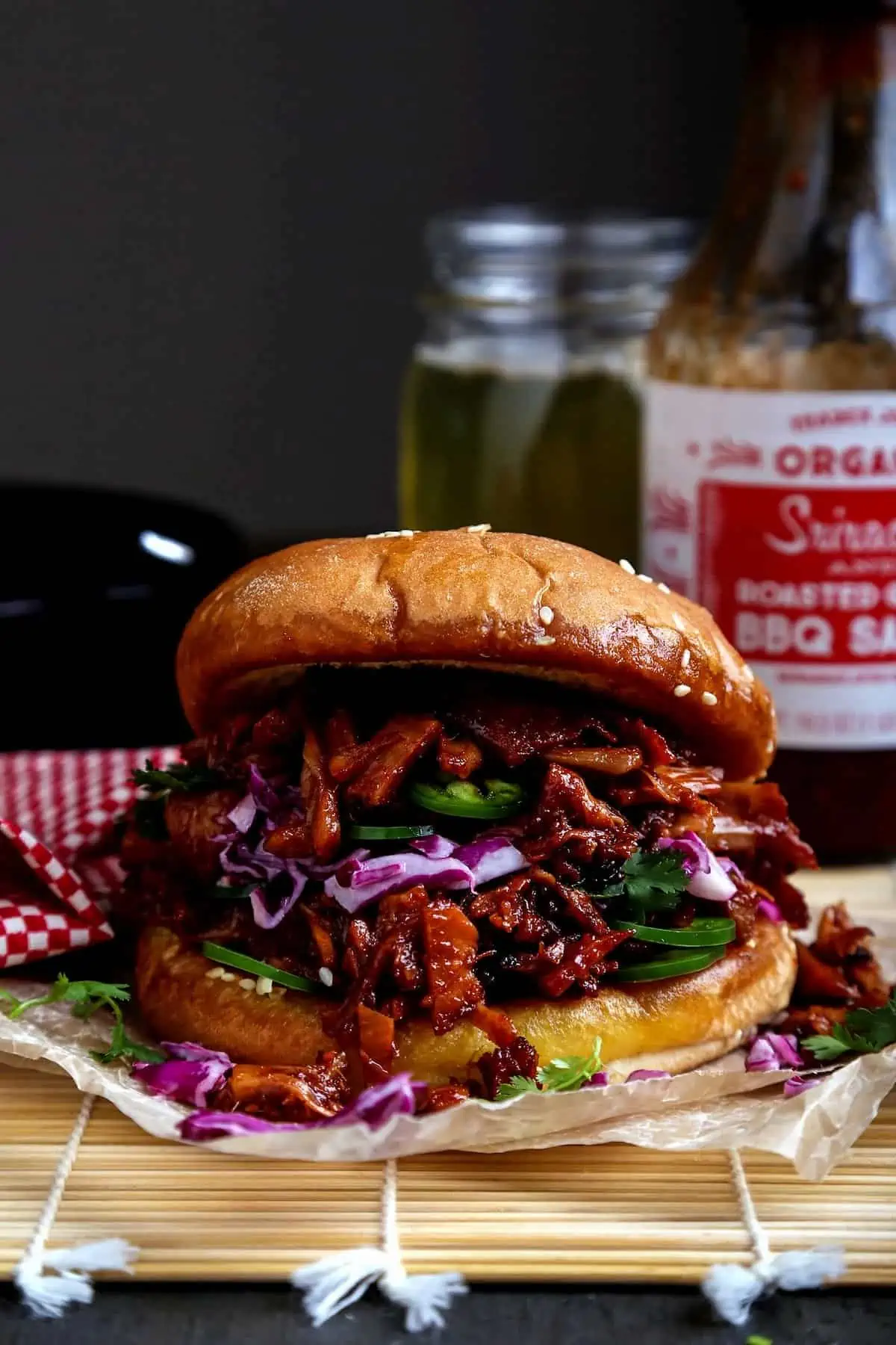 Vegan bbq pulled pork on a bun served with sliced red cabbage and jalapenos.