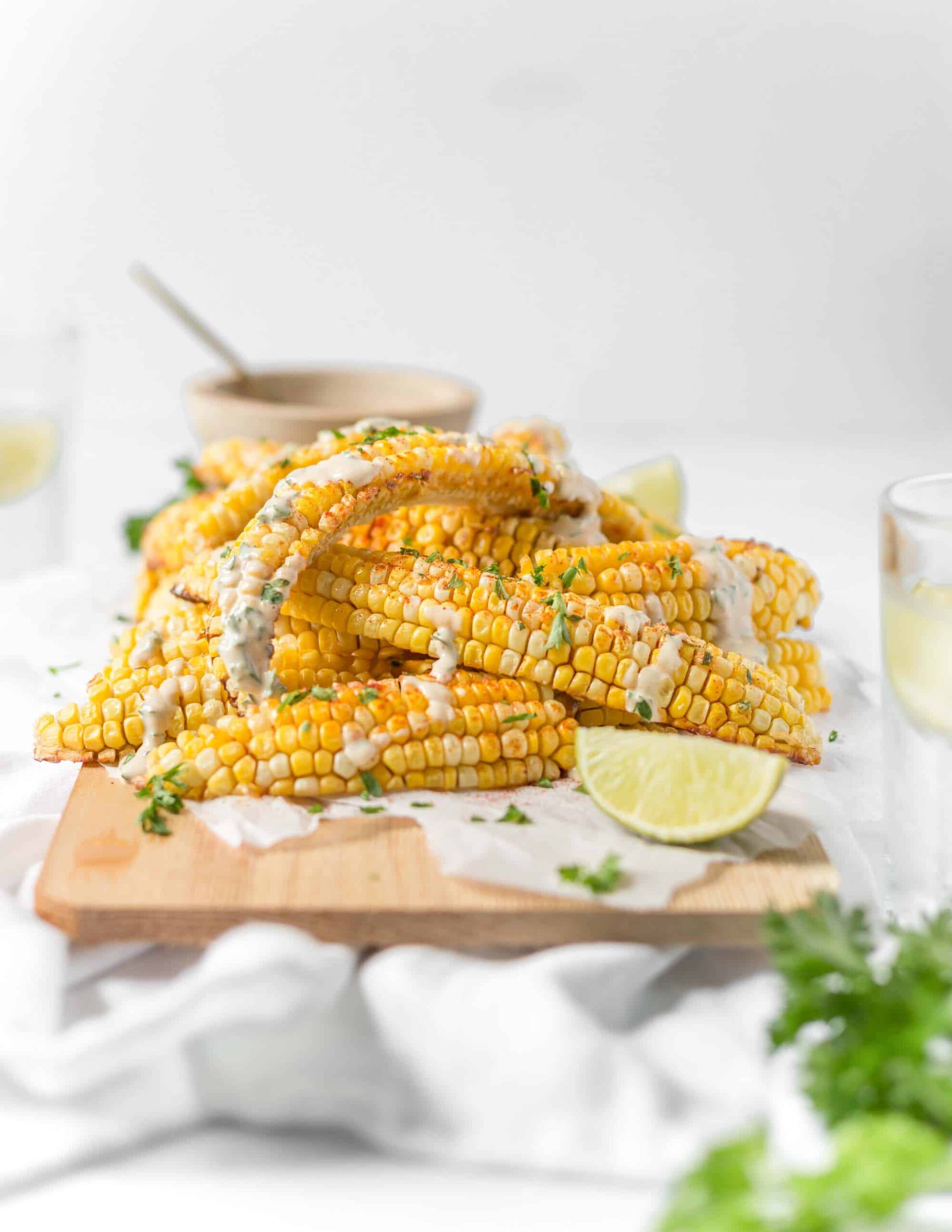 air fried corn ribs stacked on top of each other with vegan dressing and a lime wedge on the side
