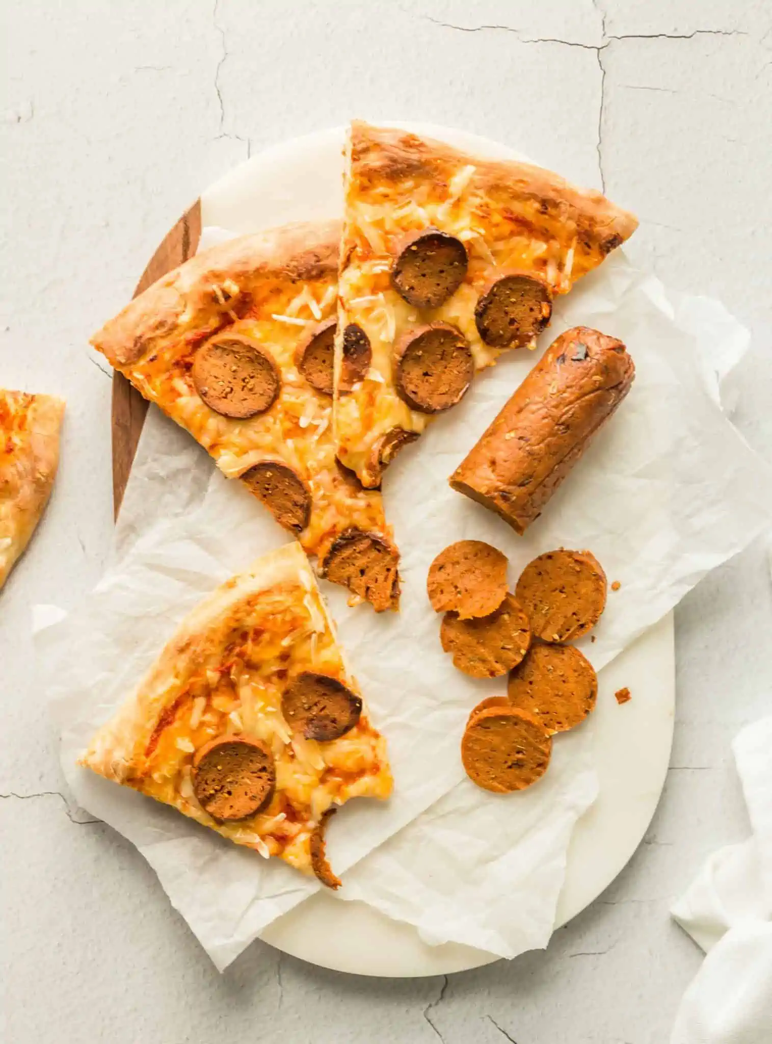 Homemade Vegan Pepperoni Pizza With Sliced Pepperoni On a Cutting Board.