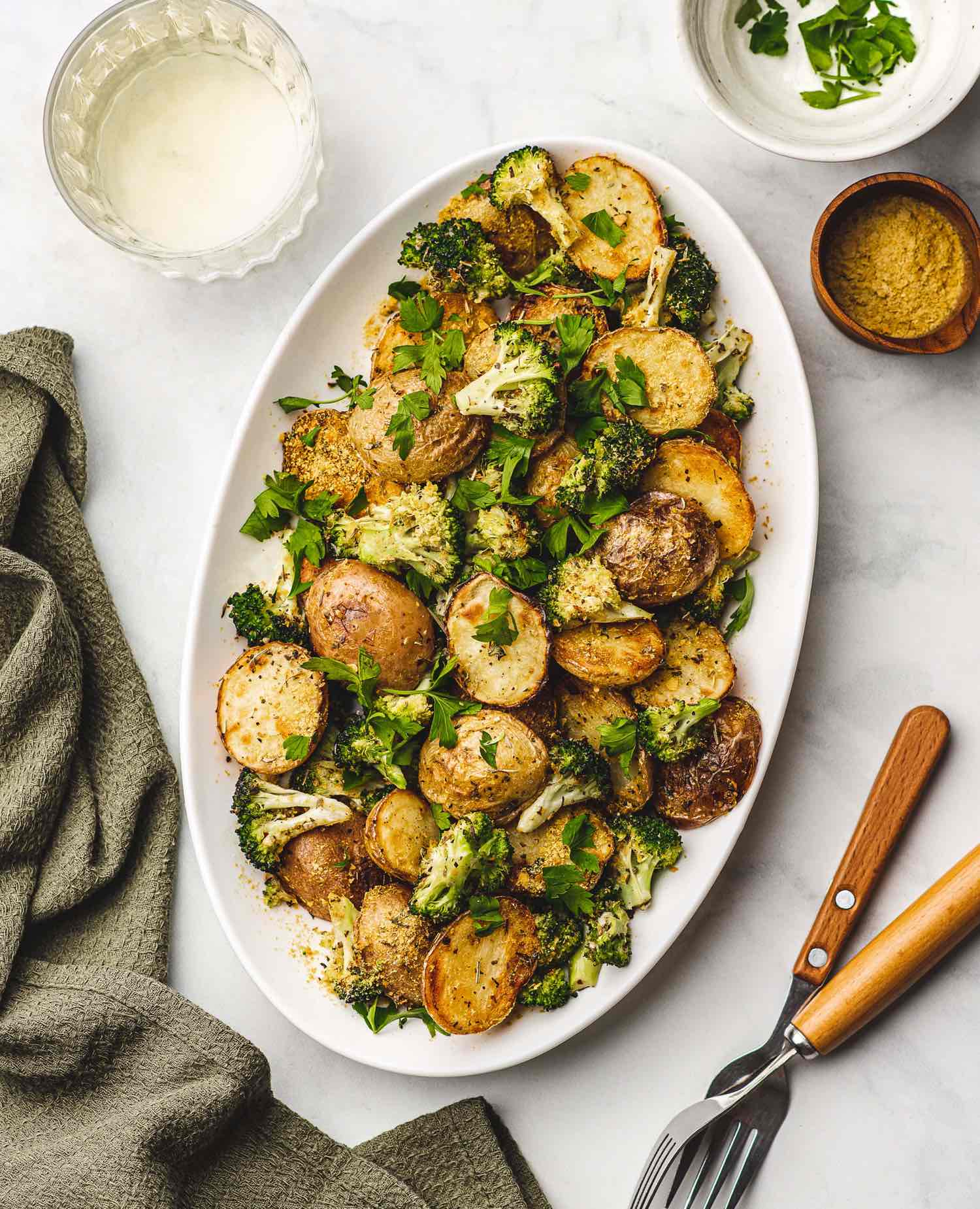 Vegan Cheesy Garlic Roasted Potatoes and Broccoli on a Platter Garnished with Parsley