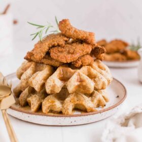 Vegan Chicken and Waffles Recipe Stacked on a Rustic Plate With Gold Cutlery