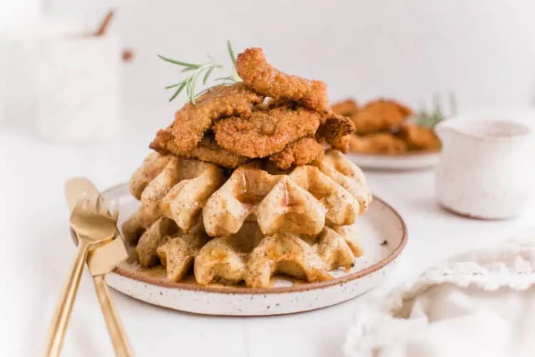 Vegan Chicken and Waffles Recipe Stacked on a Rustic Plate With Gold Cutlery