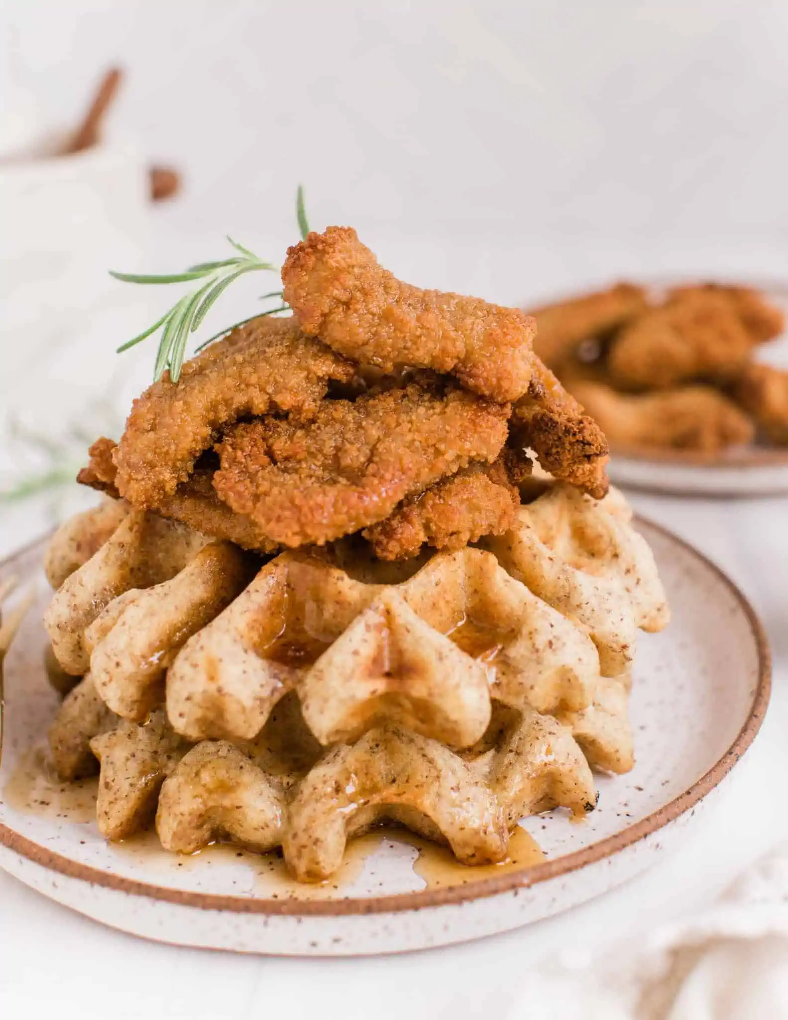 Vegan Chicken and Waffles Stacked on a Plate Topped With Air Fried Nowadays Nuggets and Maple Syrup