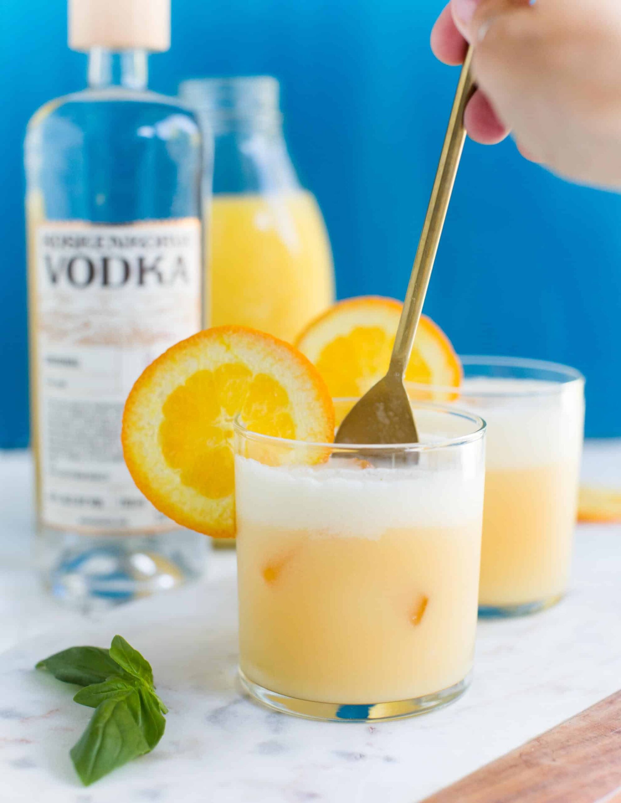 Vegan Drinks and Dairy-Free Creamsicle Cocktails Stirring with a Long Gold Spoon 