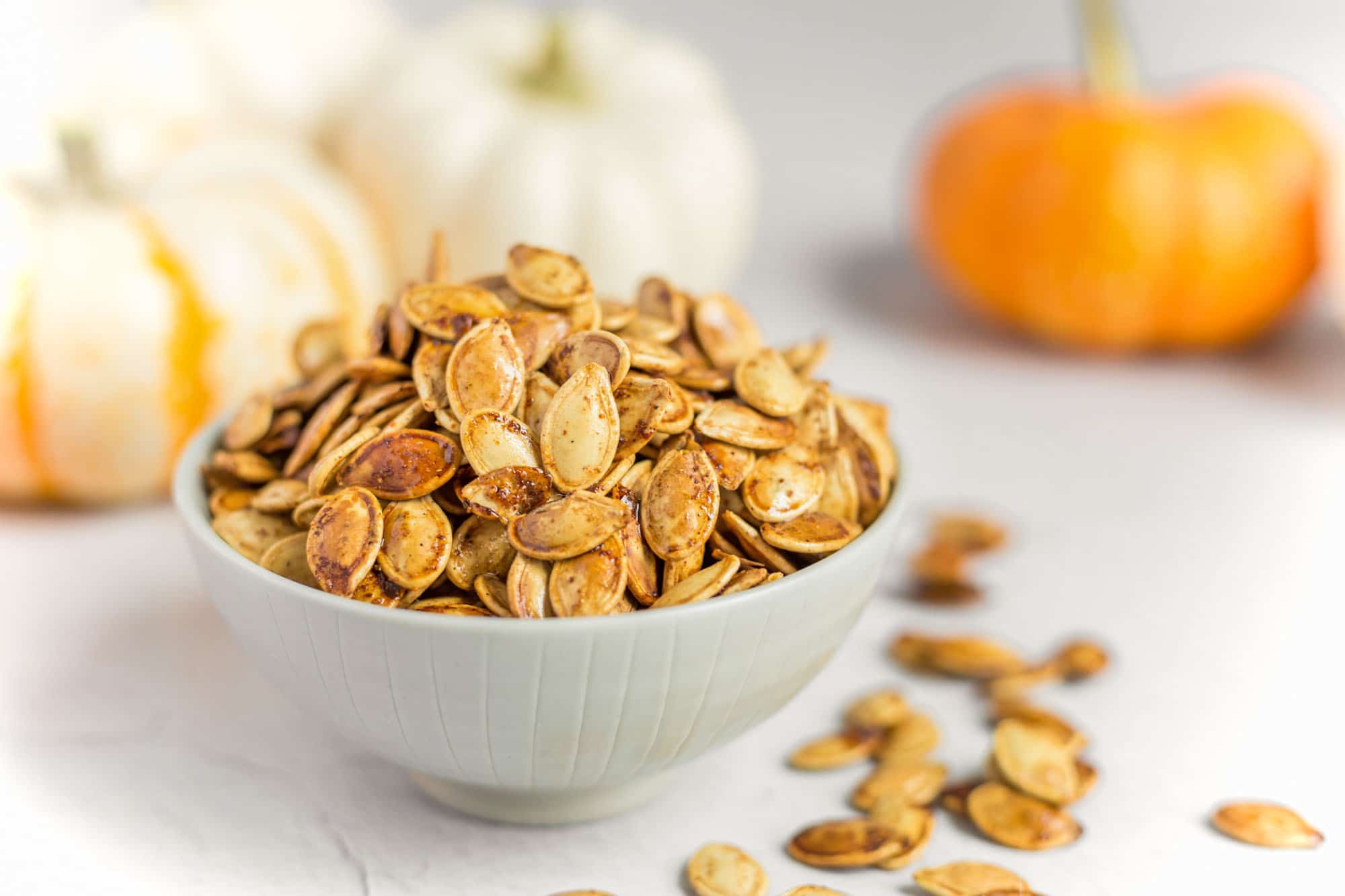 Best Roasted Pumpkin Seeds Recipe Served in a Bowl Surrounded by Pumpkins