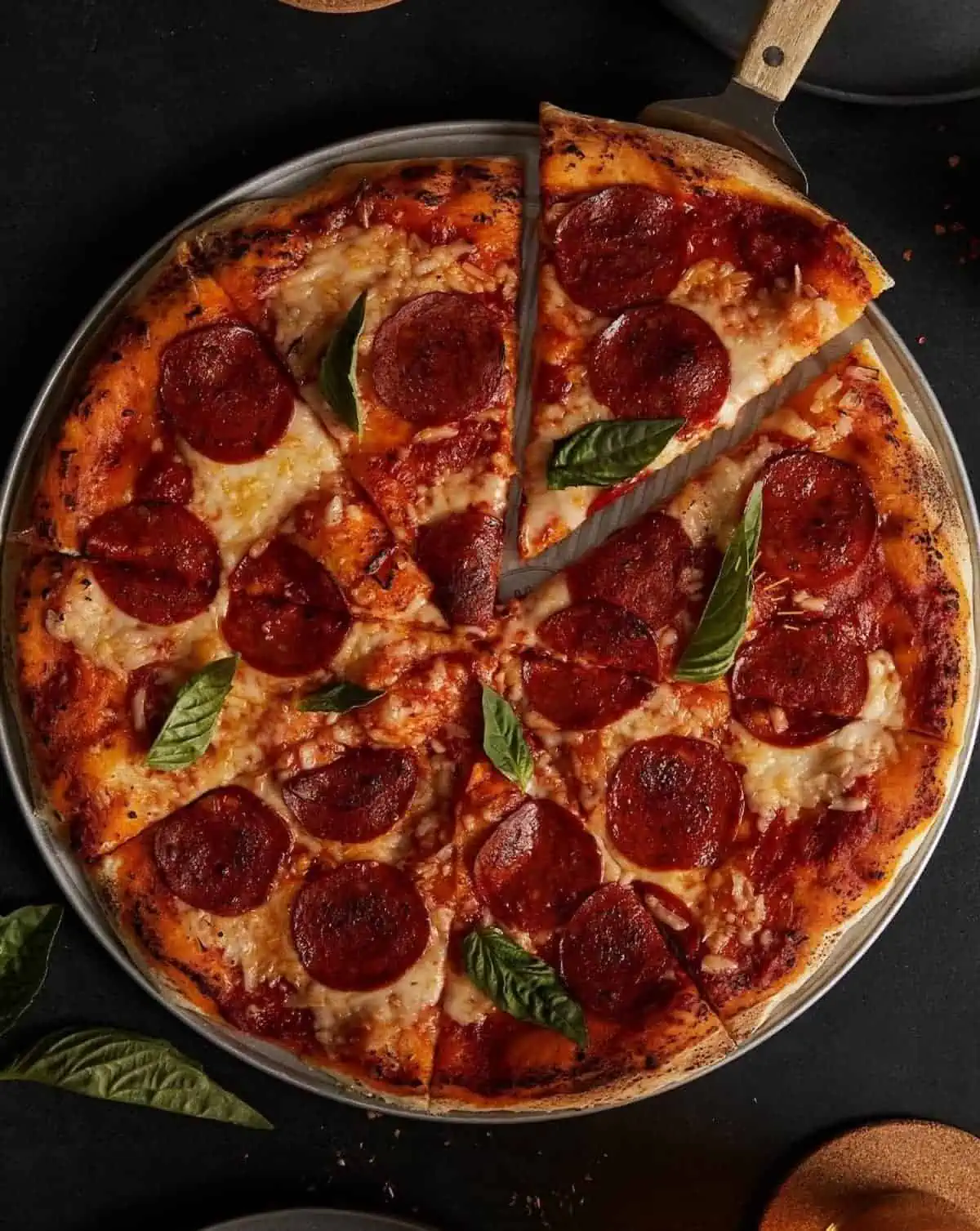 A vegan pepperoni pizza against a dark background.