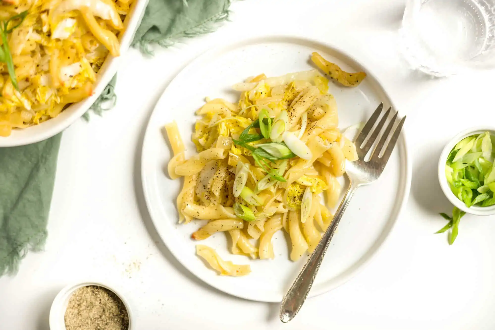 Vegan Cabbage and Noodles Casserole Served on a White Plate With Green Scallions