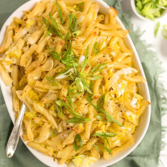 Vegan cabbage and noodles with sautéed cabbage and pasta in a white oval bowl.