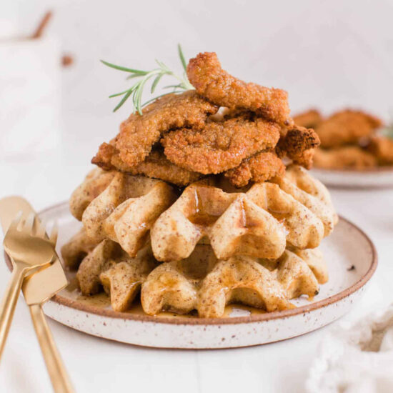 Vegan chicken and waffles served on a plate and drizzled with maple syrup.