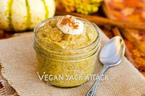 Easy Vegan Pumpkin Chia Pudding in a glass jar serve with a spoon and topped with vegan whipped cream and cinnamon.