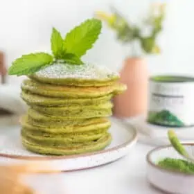 Stack of Green Vegan Matcha Pancakes With Powdered Sugar and a Mint Leaf.
