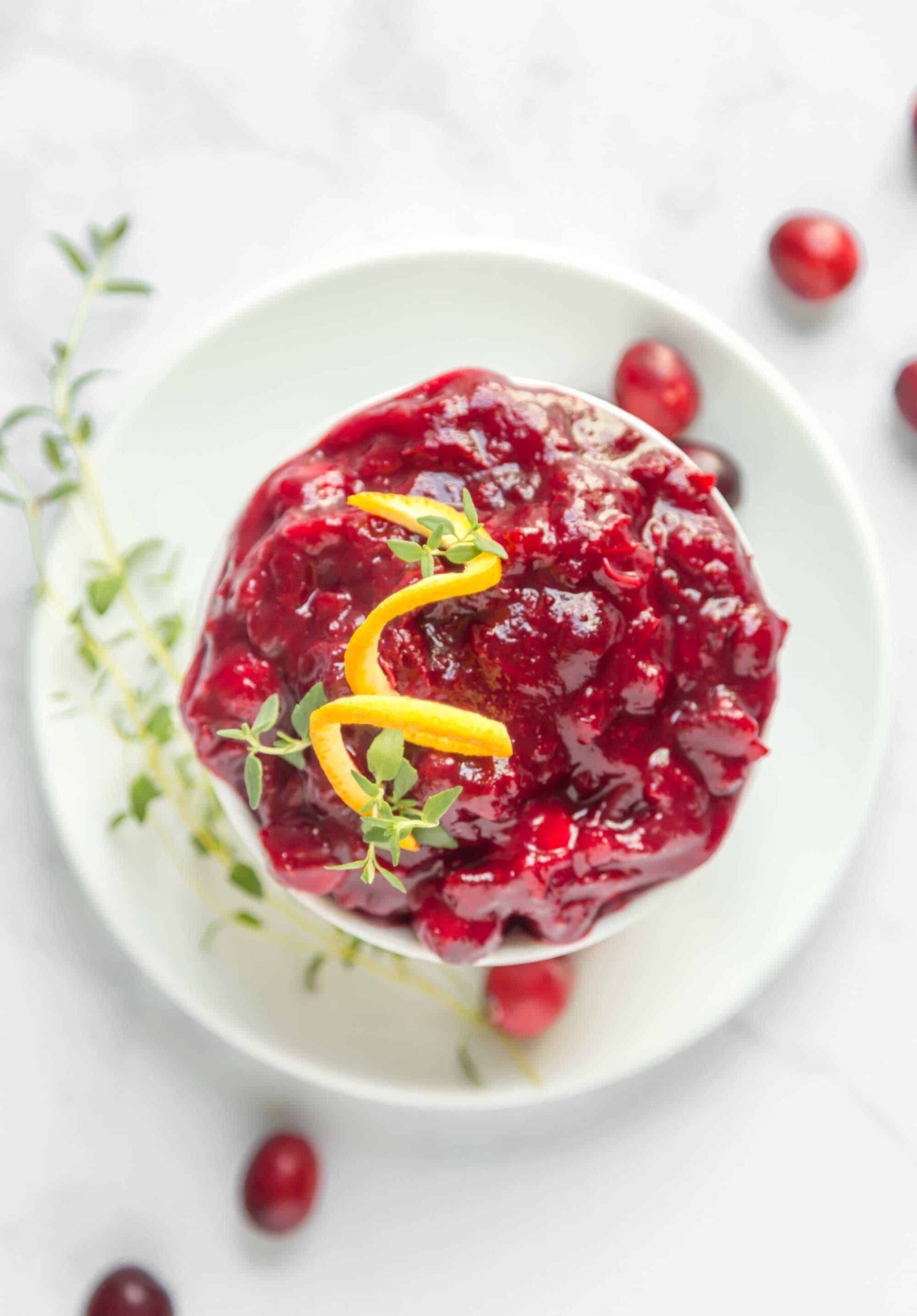 Cranberry sauce in a bowl topped with a spiraled orange peel.
