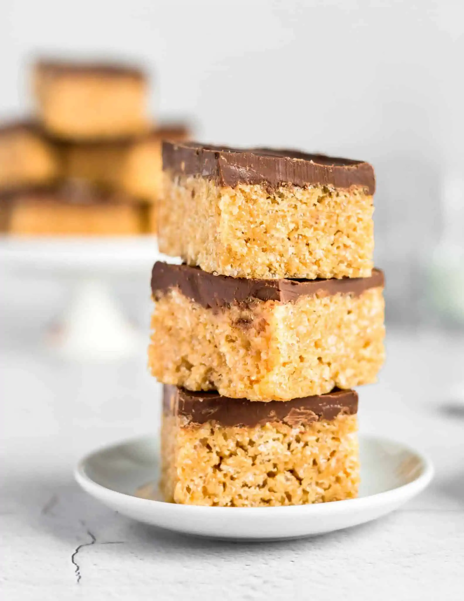 Vegan caramel squares called Scotcharoos stacked up on a plate. 