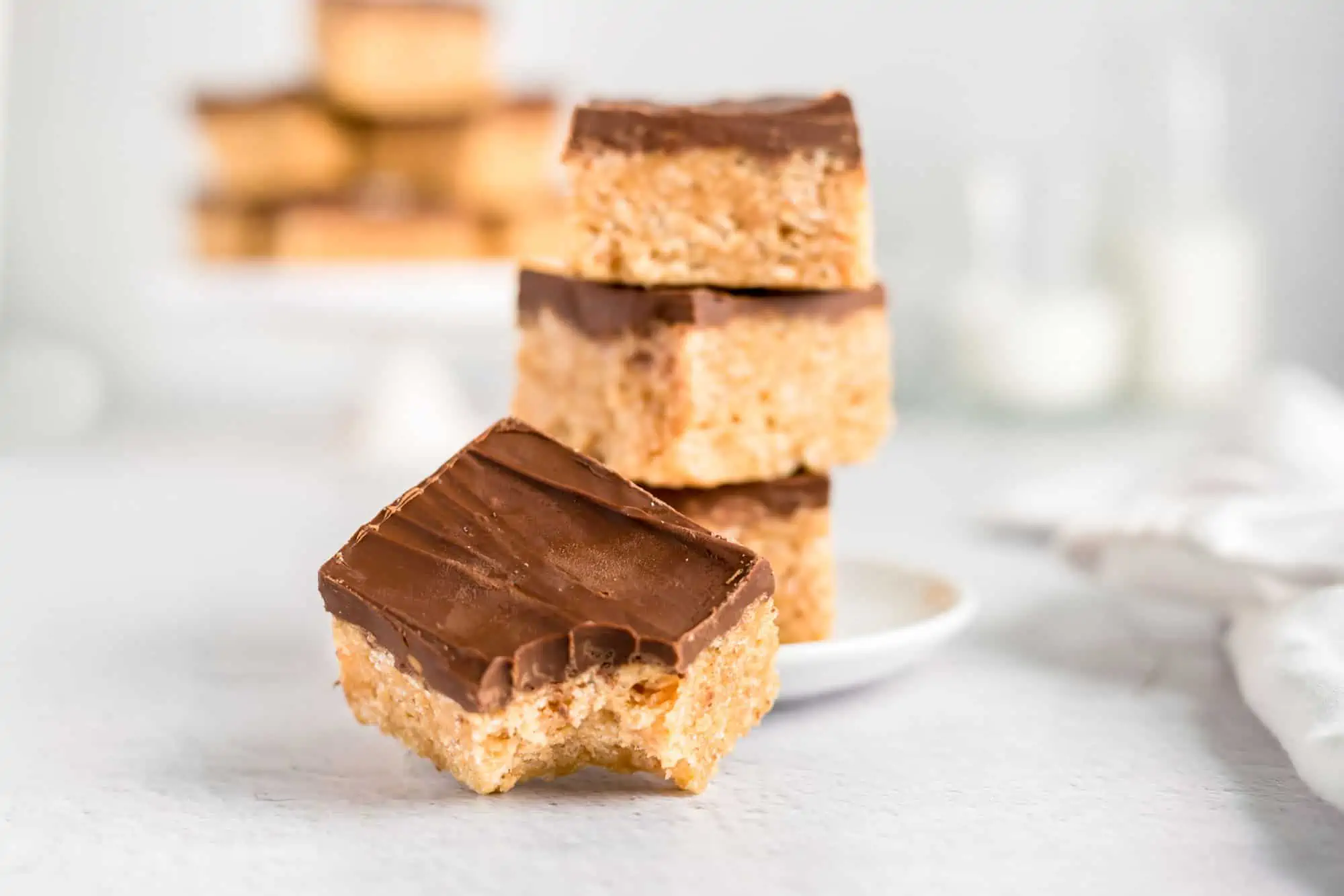 Gluten-free vegan dessert scotcharoo bars stacked on a plate with one missing a bite.