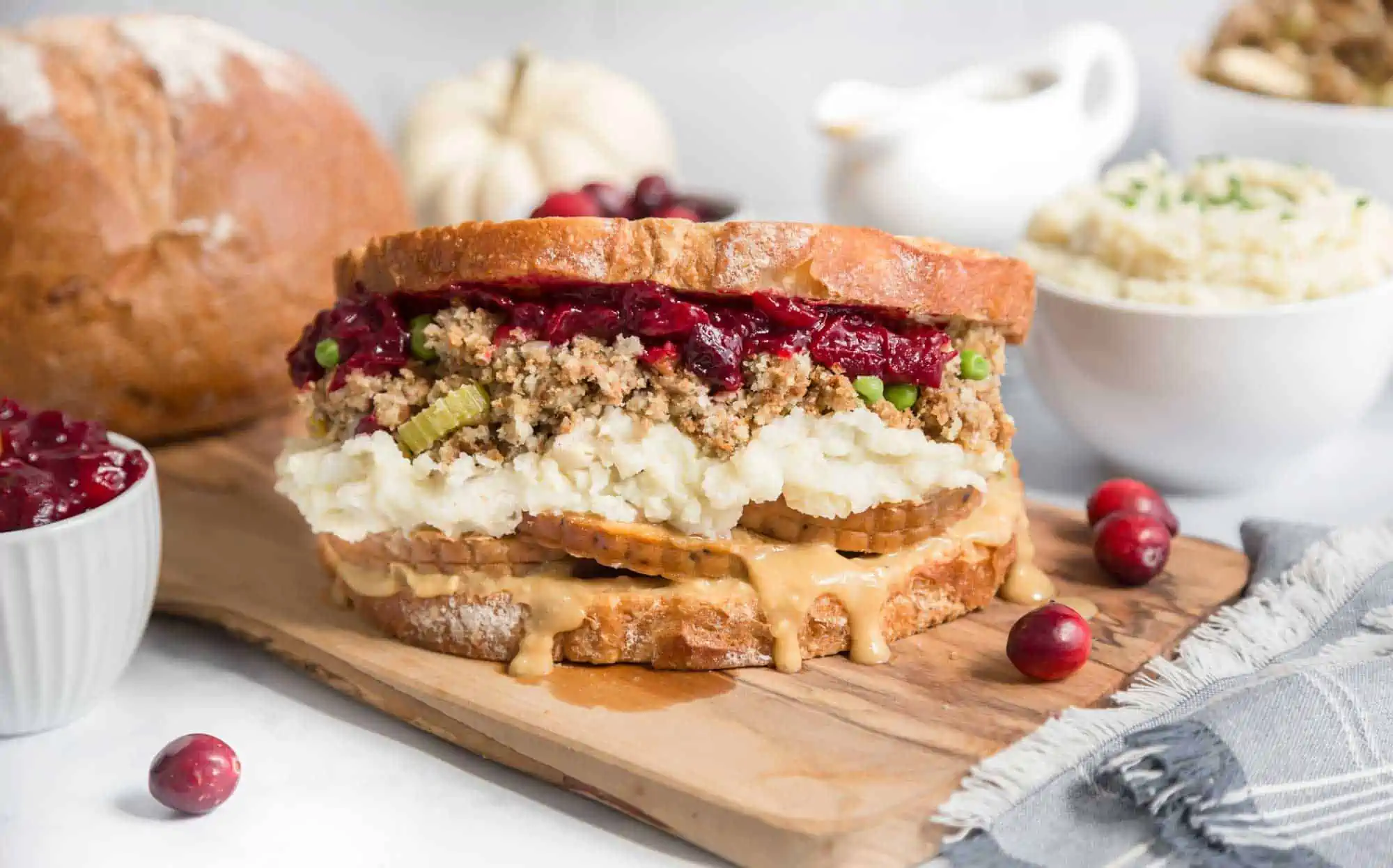 An air-fried vegan Thanksgiving leftovers sandwich on a wooden serving board.