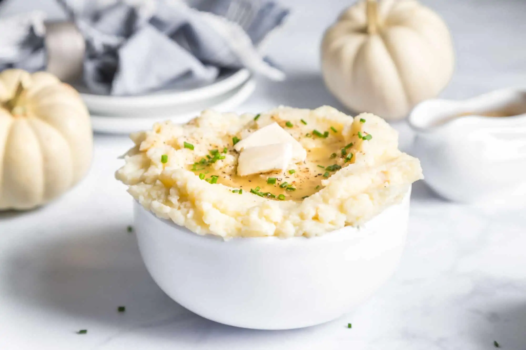 Best Dairy-Free Mashed Potatoes In a White Bowl With Vegan Butter and roasted Garlic