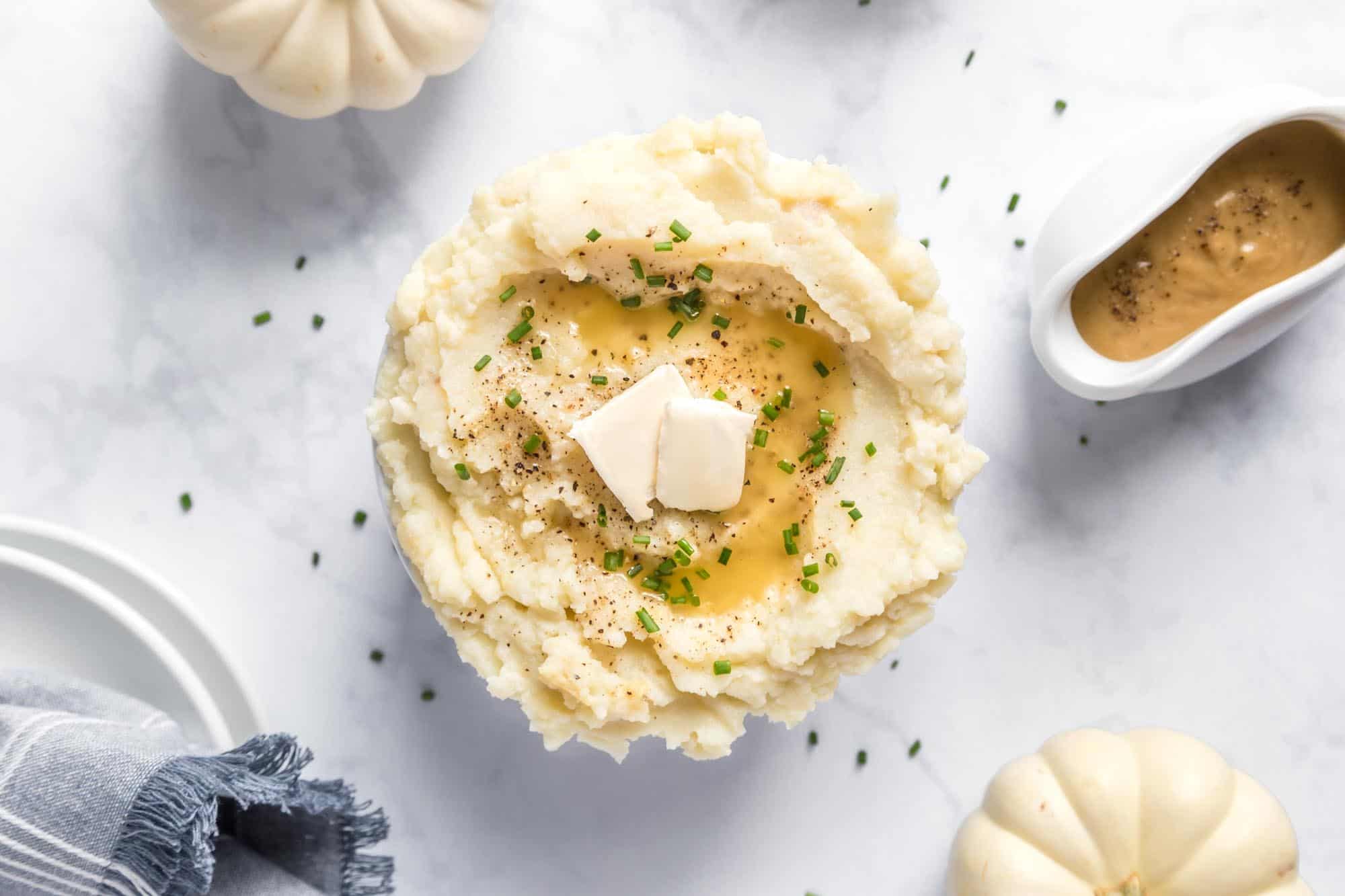 Mashed potatoes with a saucer of vegan gravy next to it. 