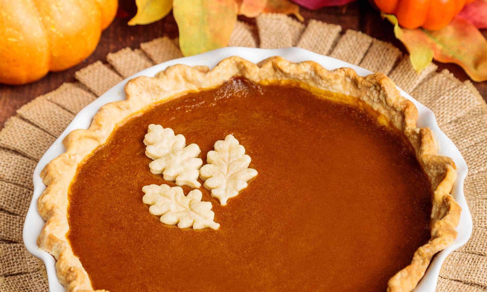 Vegan pumpkin pie with fall decorations around it.