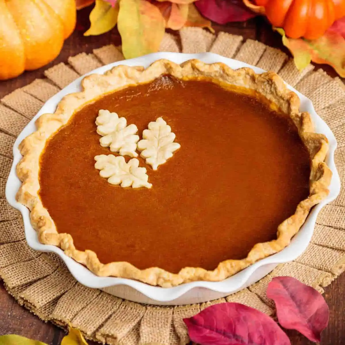 Vegan pumpkin pie with fall decorations around it.