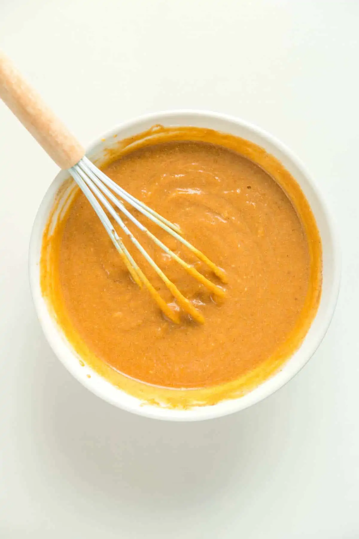 Vegan pumpkin pie filling mixed in a large bowl with a whisk.
