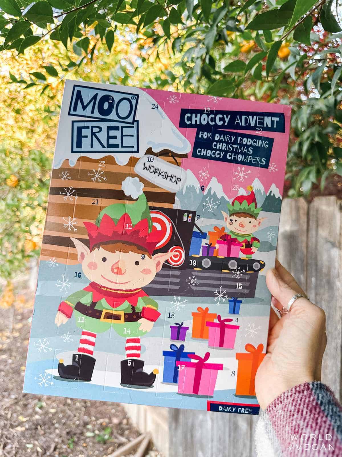 Woman holding up a Moo-Free advent calendar filled with vegan holiday chocolates.