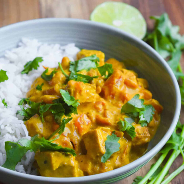 Indian vegan butter chicken in a bowl with rice and fresh cilantro leaves.