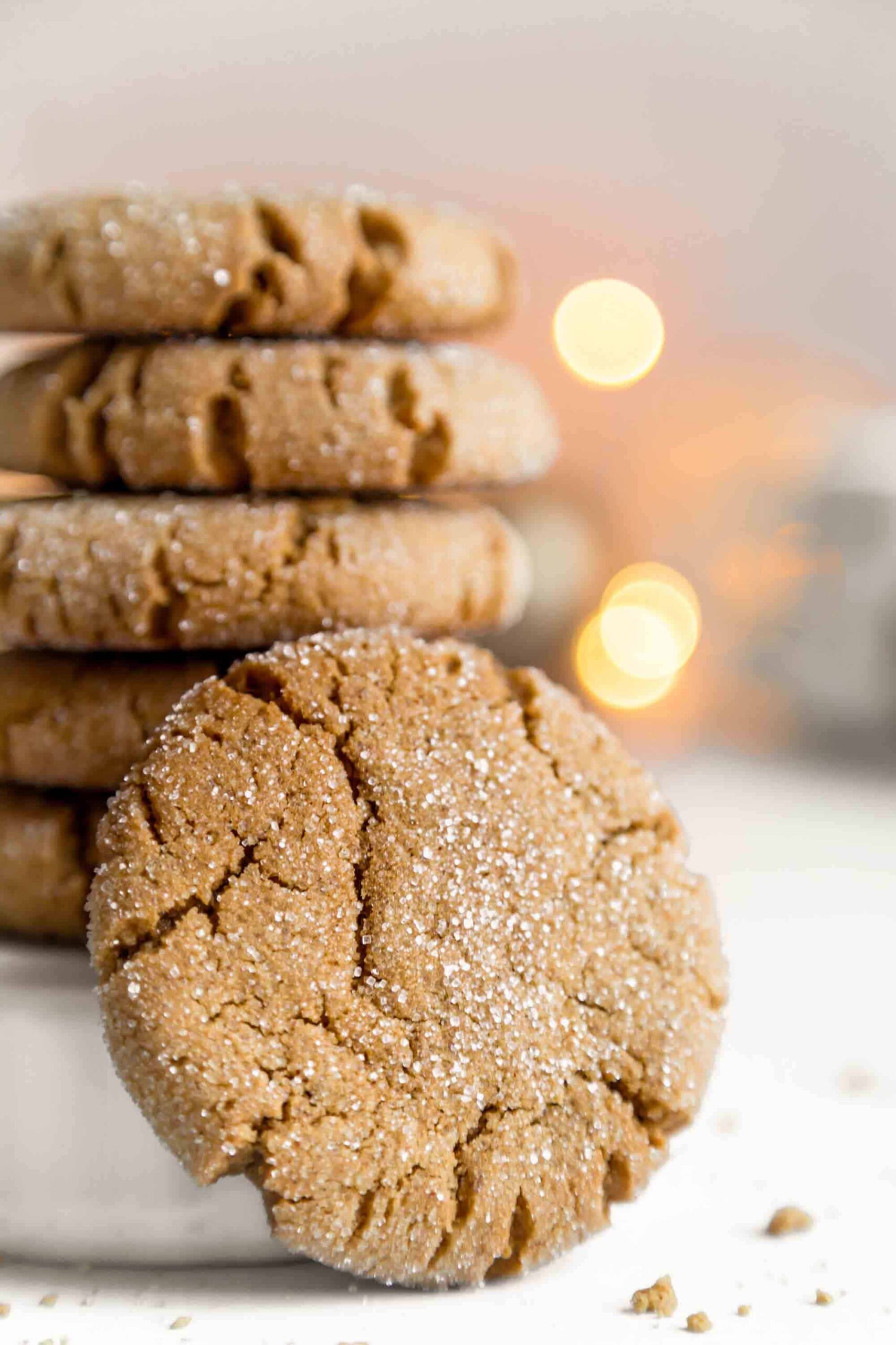 Stack of Dairy-Free Gingersnap Cookies With Christmas Lights in Background
