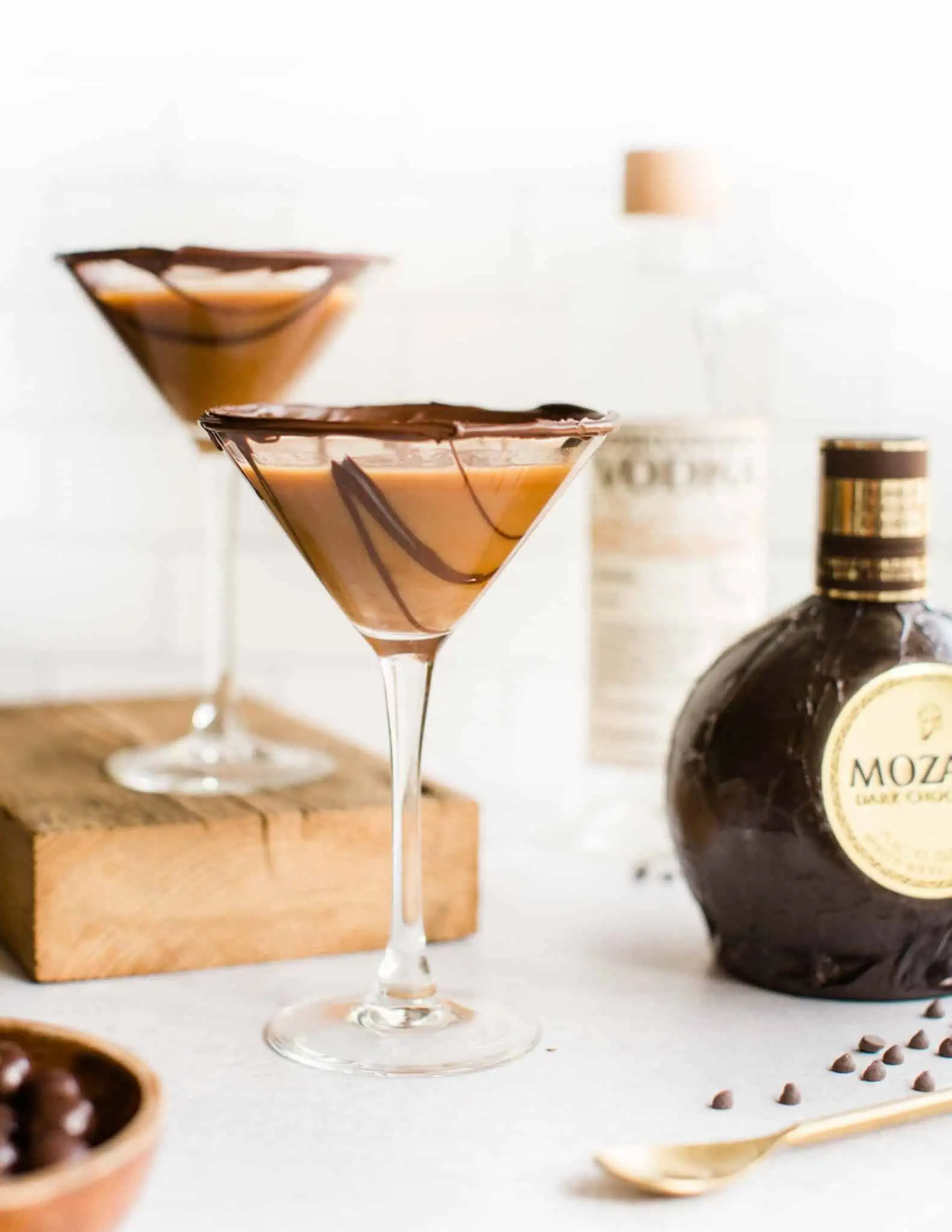 Two martini glasses with decorative chocolate drizzle and mini chocolate chips.