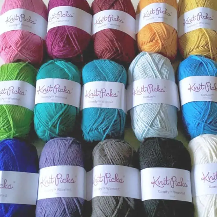 A rainbow of vegan yarn colors laid out on a table.