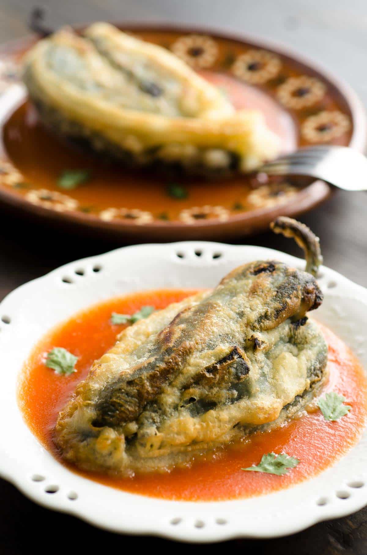 vegan chiles rellenos on a plate with red sauce