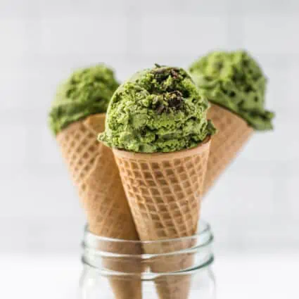 Three waffle cones filled with scoops of vegan matcha ice cream.