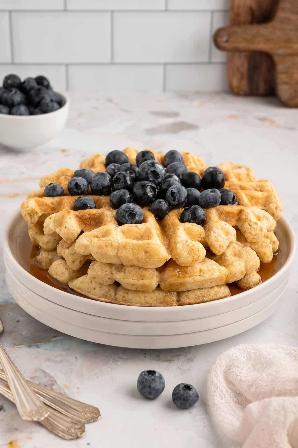 A stack of vegan waffles, topped with blueberries.
