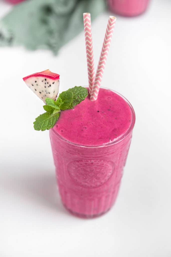 Bright Pink Dragon Fruit Smoothie served in a glass with a slice of pitaya and sprig of mint