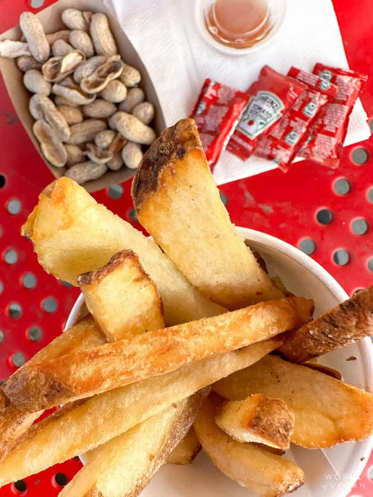 Five Guys fries and peanuts and ketchup on a red outdoor table. 