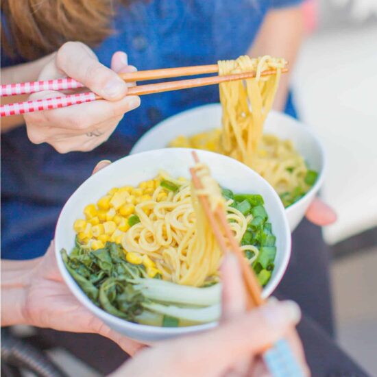 michelle cehn and toni okamoto eating the friendly vegan cookbook ramen noodle soup