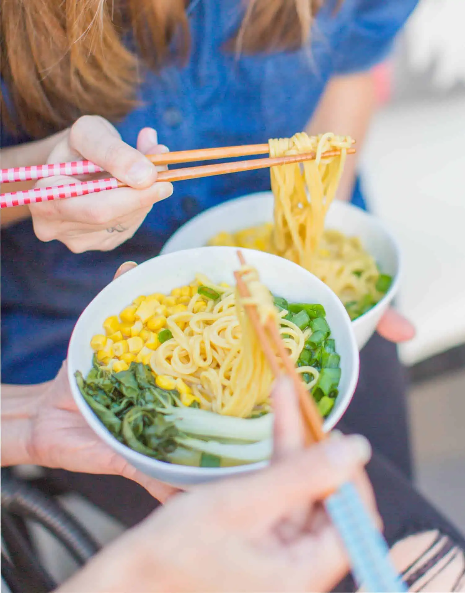 michelle cehn and toni okamoto eating the friendly vegan cookbook ramen noodle soup