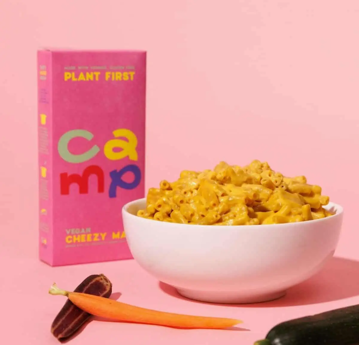 A bowl full of Camp's vegan cheezy mac and cheese next to the box.
