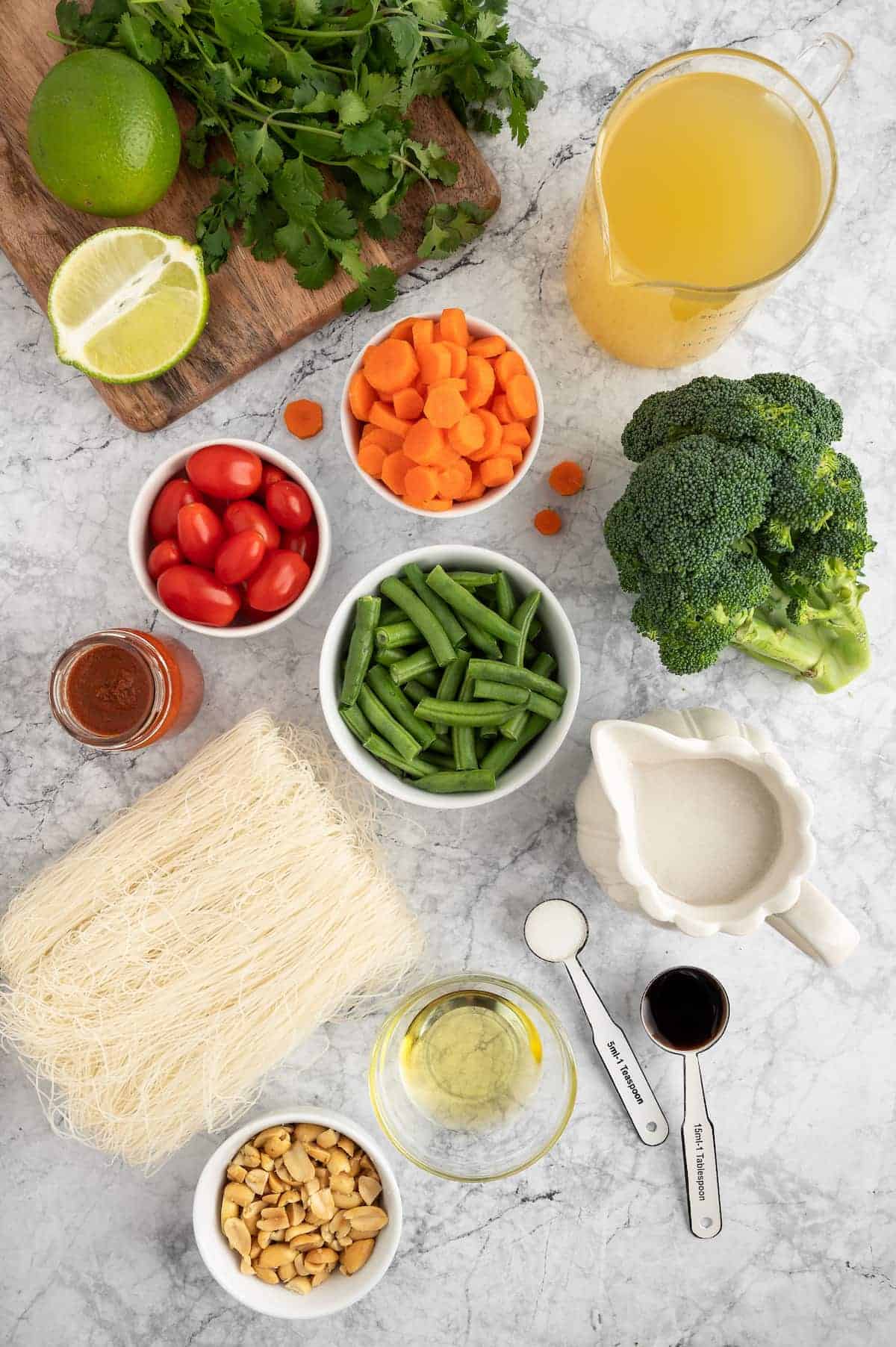 An arrangement of key ingredients for vegan Thai curry against a marble background.