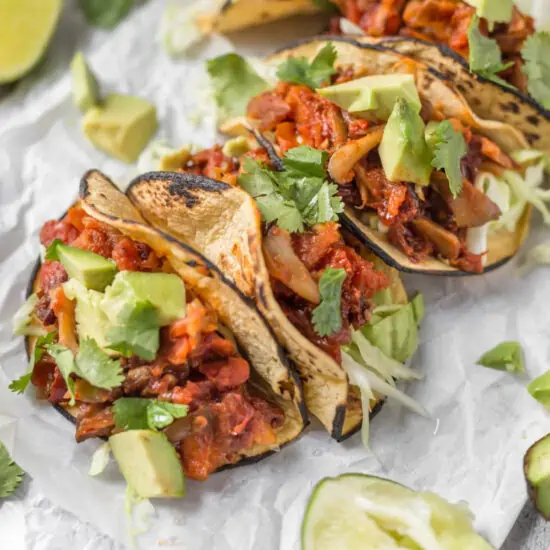 Vegan Mushroom Tacos with avocado and lemon wedges.