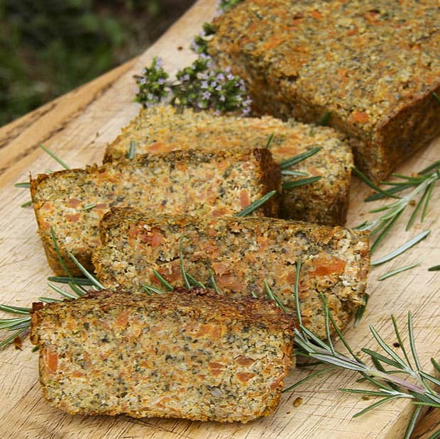 sliced up carrot and seed loaf on a plate with herbs