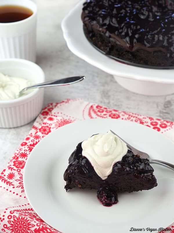 chocolate cherry cheesecake on a plate with vegan whipped cream