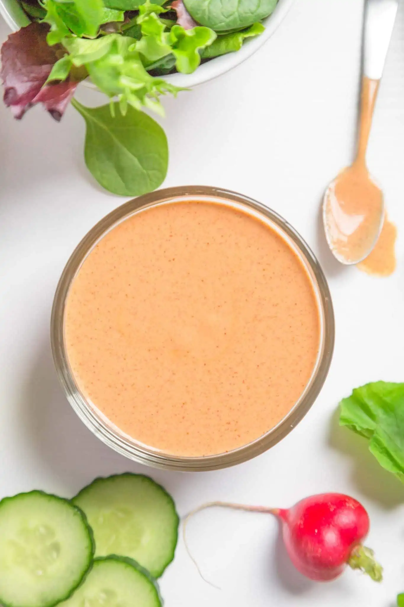 vegan french dressing made with cashews in a bowl with salad cucumbers and radish 