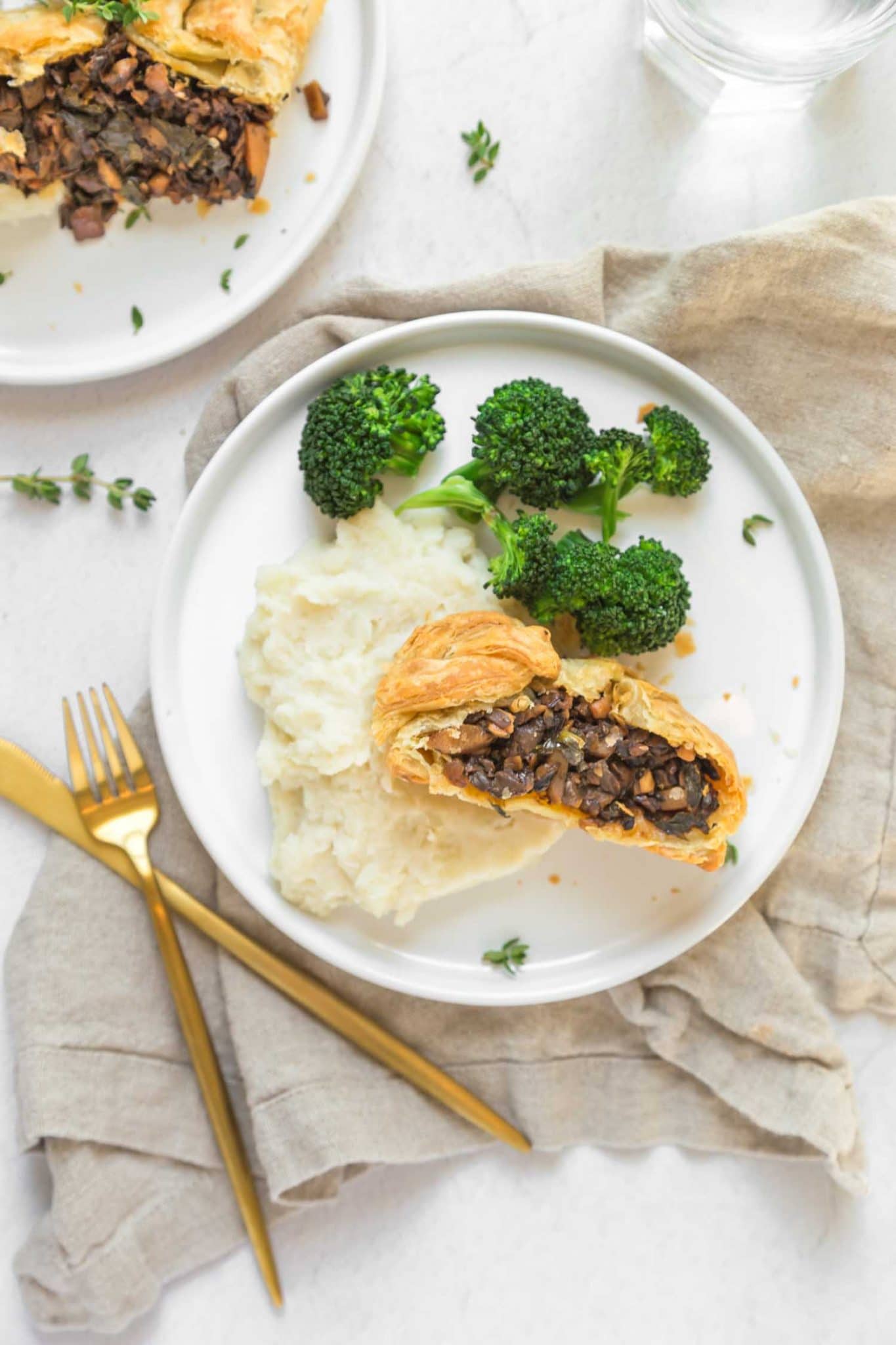 slice of mushroom wellington served with broccoli and mashed potatoes on a plate