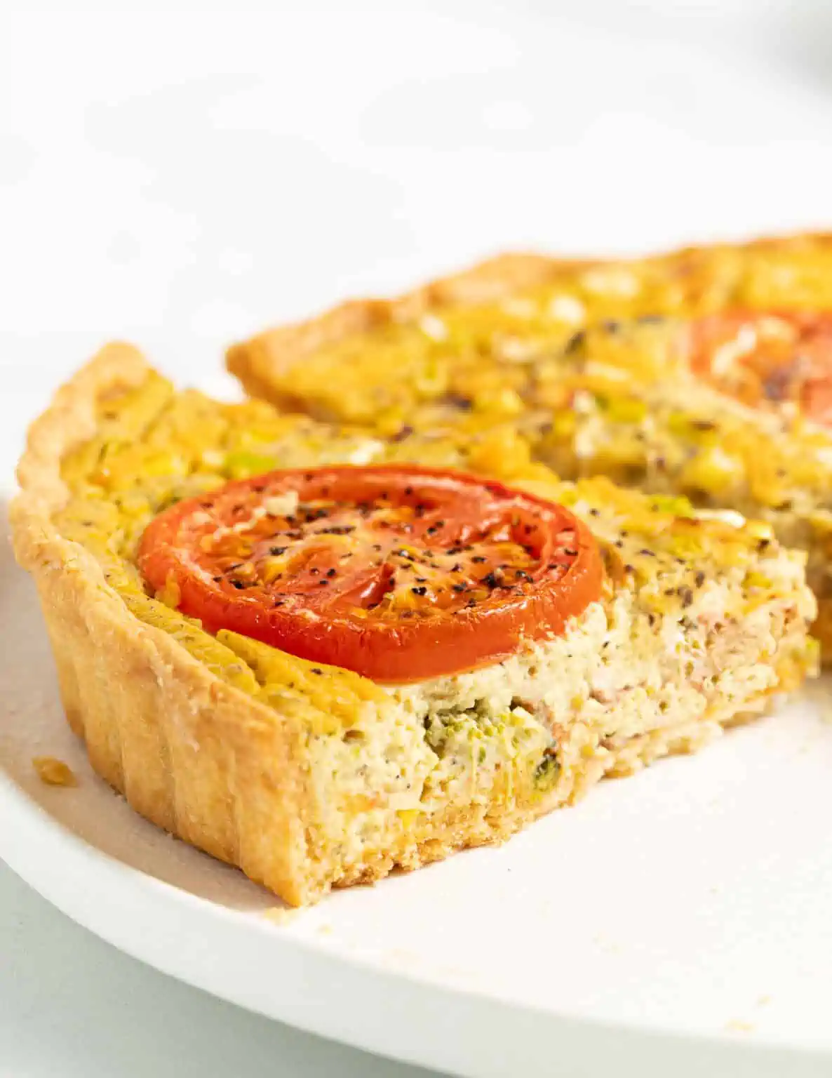 vegan quiche slices with tomato on top on a plate