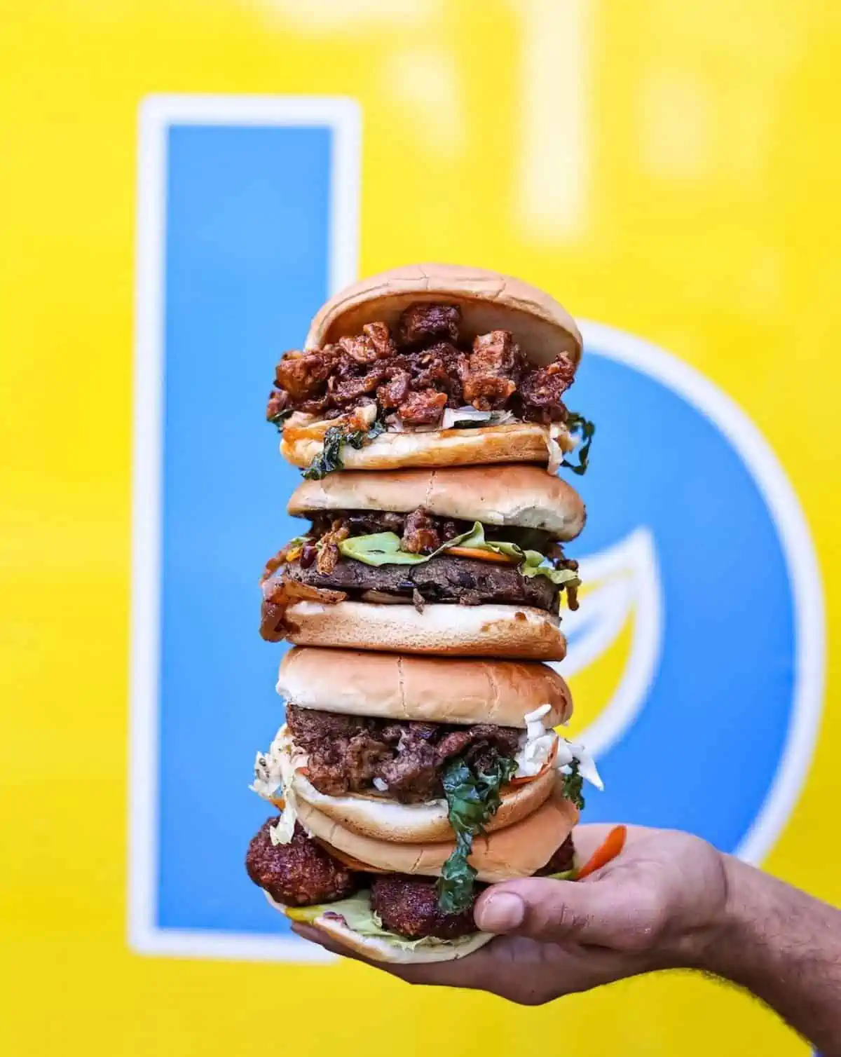 A hand holding a stack of vegan burgers.